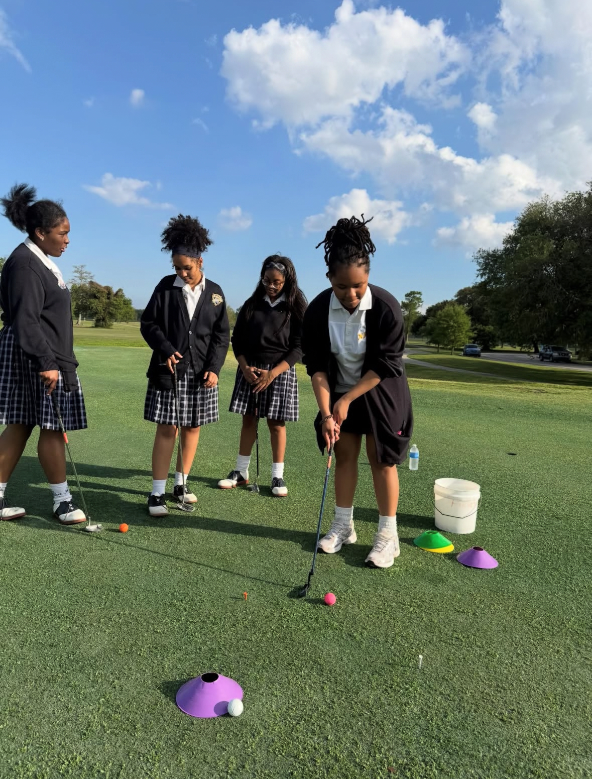 Girls practicing putting on the green